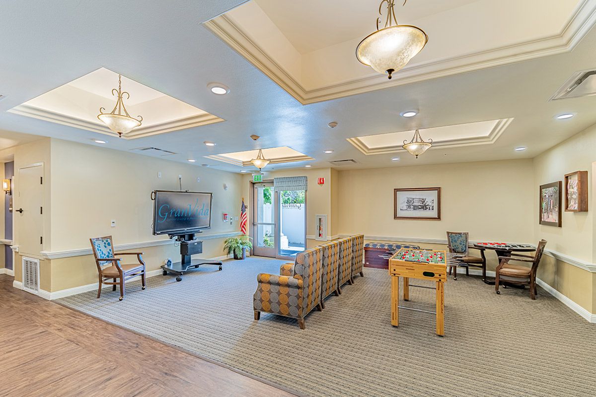 A spacious lounge area with comfortable seating, a television, and a foosball table.