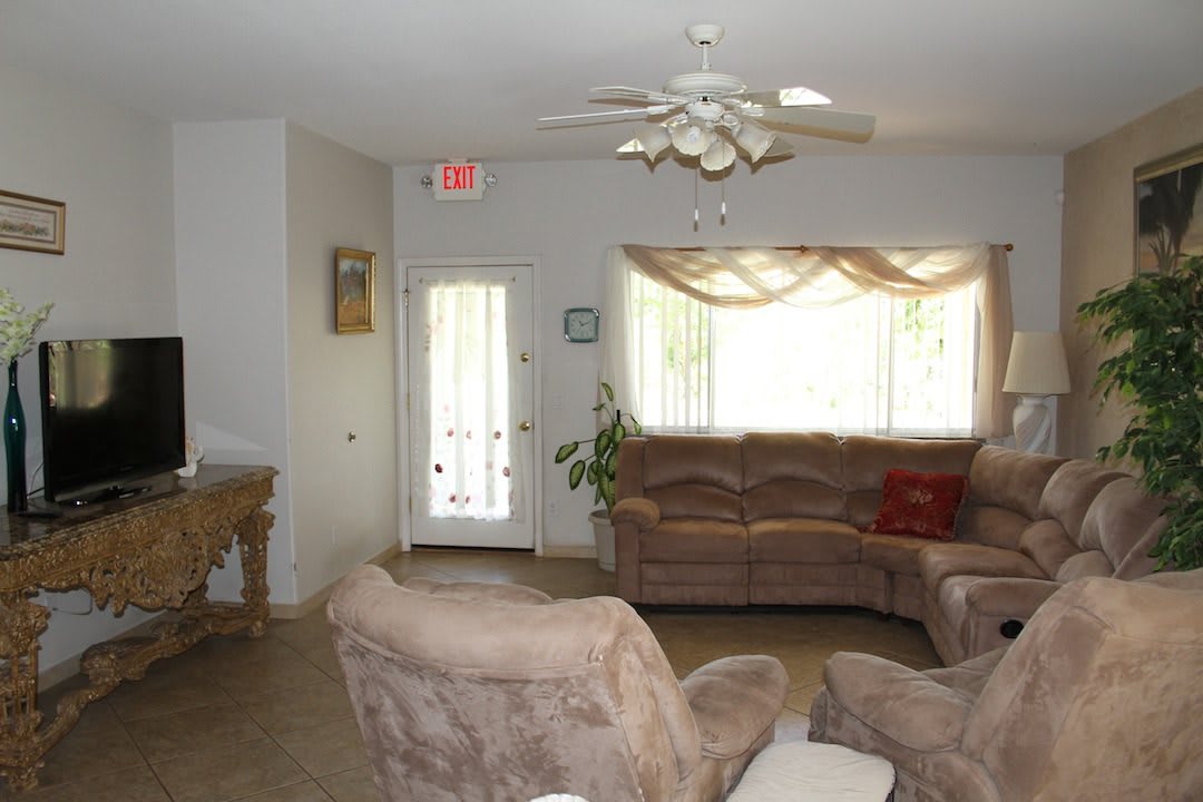 A cozy living room with comfortable seating and a ceiling fan.