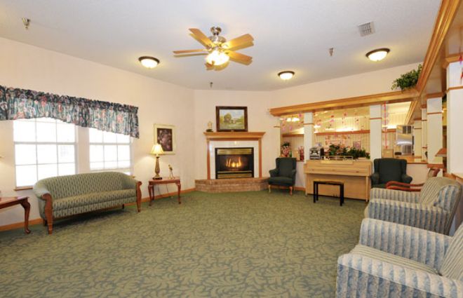 A cozy living room with a fireplace, various seating options, and a ceiling fan.