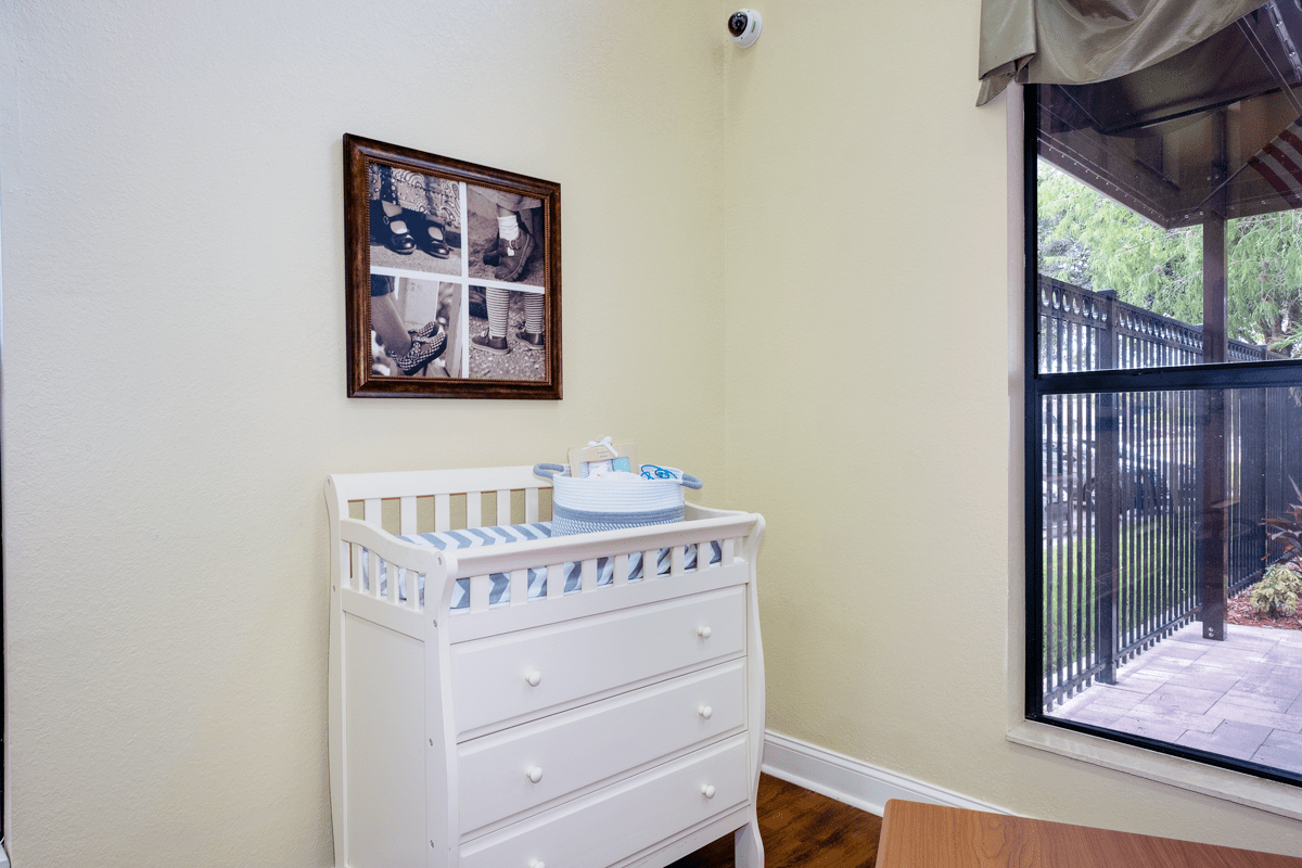 A nursery with a white changing table and framed pictures on the wall.