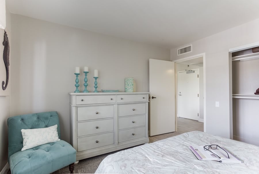 A minimalist bedroom featuring a dresser and an armchair with simple decor.