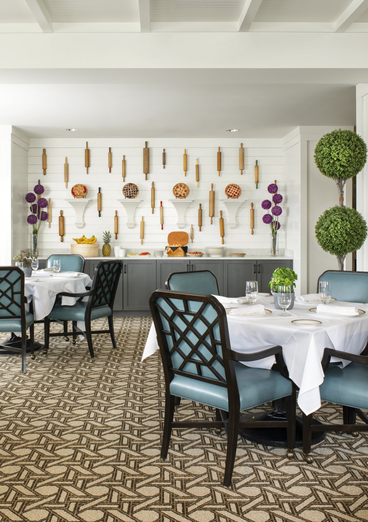 A beautifully designed restaurant dining room featuring elegant tables and chairs, with artistic wall decor and lush greenery.