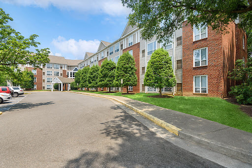 A modern apartment complex surrounded by well-maintained landscaping and blue skies.