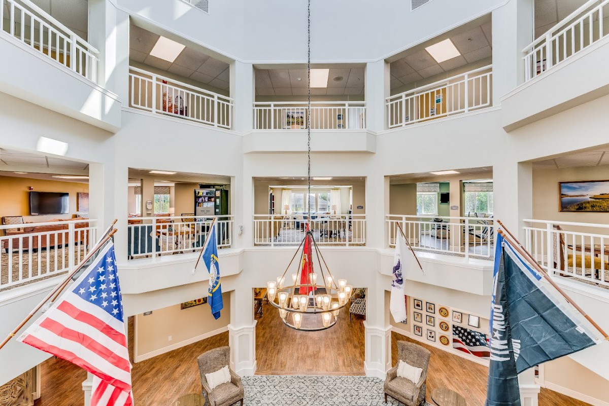A modern atrium with a chandelier and flags, surrounded by balconies.