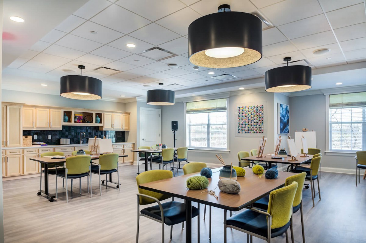 A modern dining area with contemporary lighting and furniture, featuring a kitchen in the background.