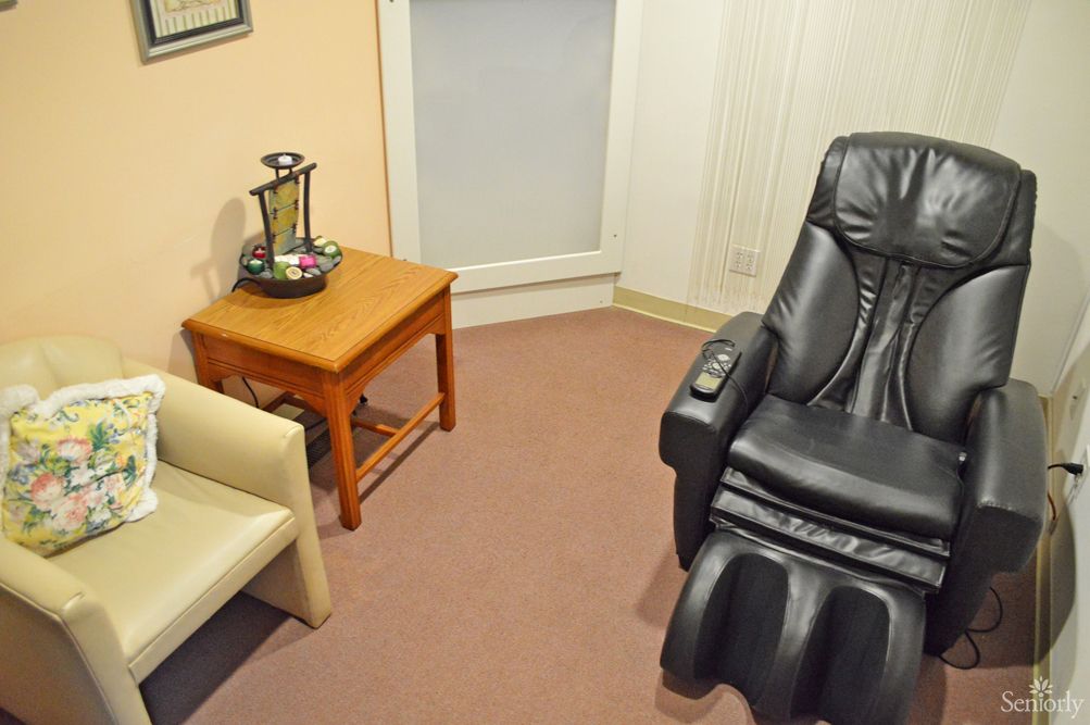 A cozy waiting room featuring a massage chair and a small table with refreshments.