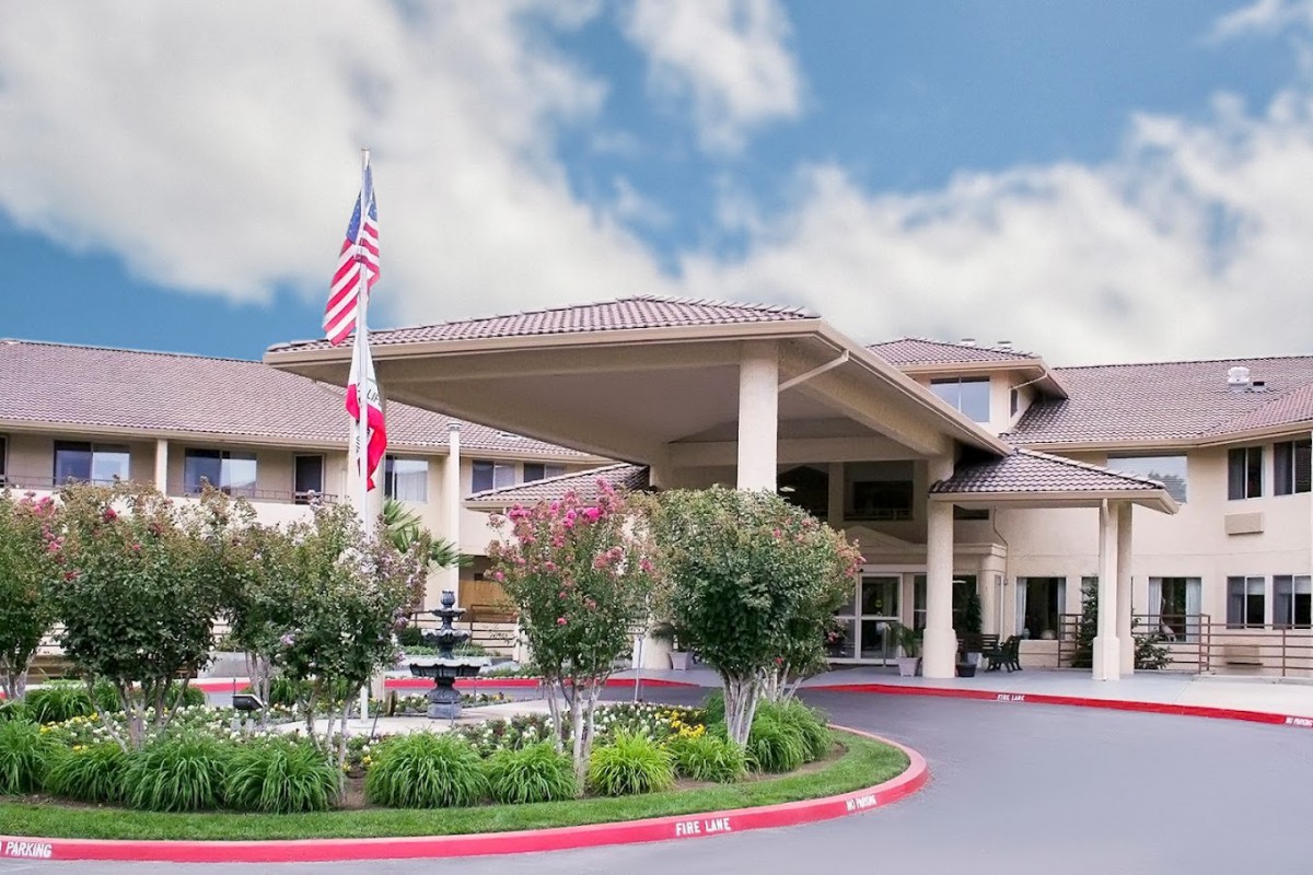 A large building entrance with flags, a fountain, and landscaped surroundings.
