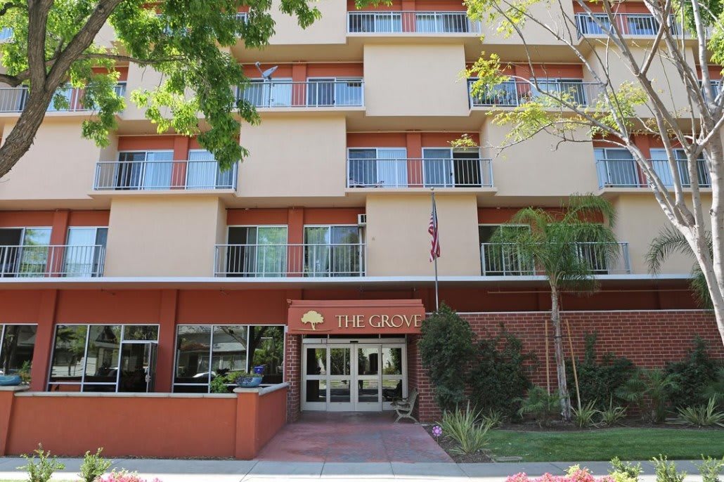 The entrance of a hotel building surrounded by trees.