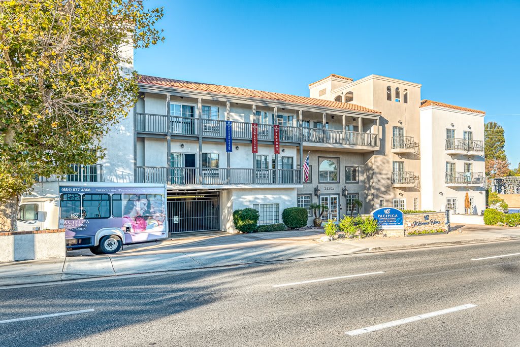 A street view of a hotel building with a bus parked in front.