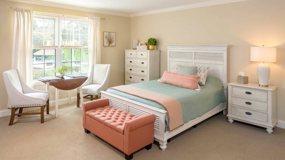 A cozy and well-decorated bedroom with a stylish bed, chest of drawers, and a soft bench at the foot of the bed.