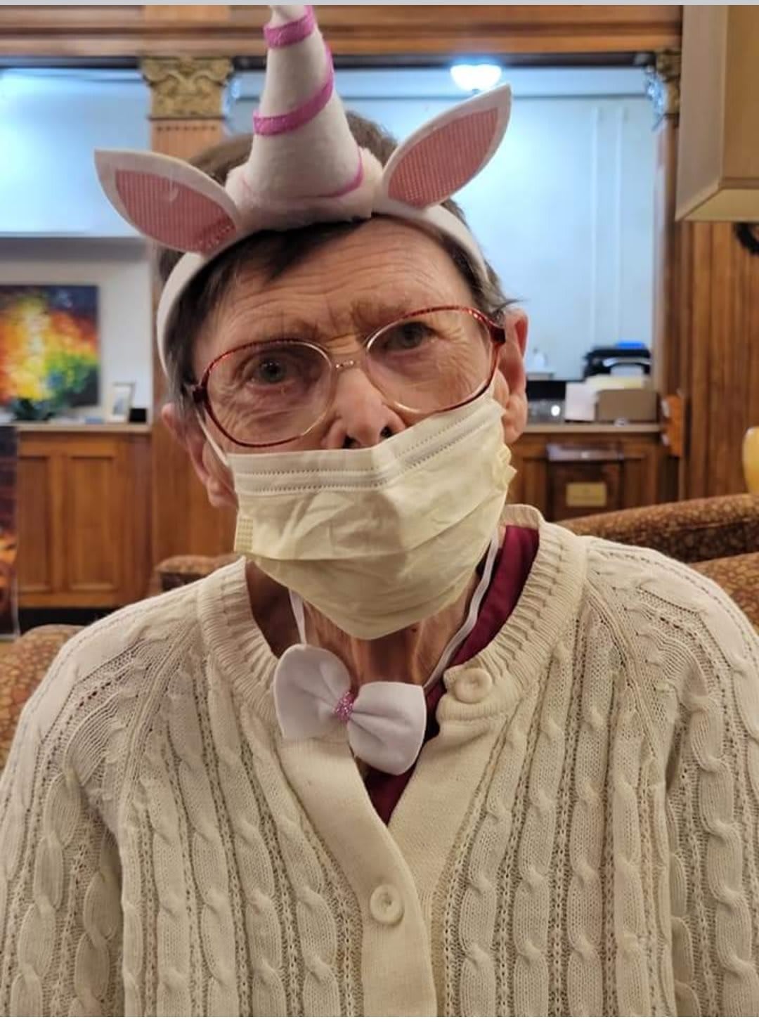 Person wearing a unicorn headband and mask indoors.