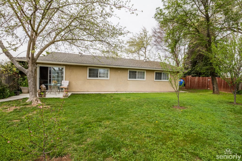 A suburban home with a grassy backyard and surrounding trees.