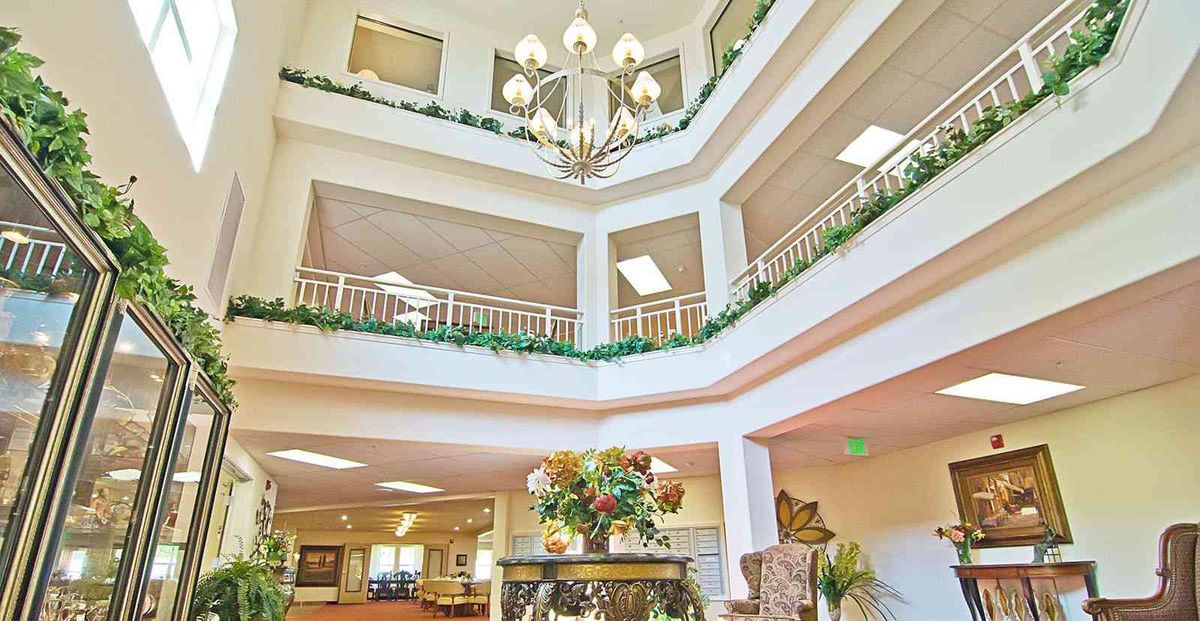 A bright and spacious atrium with a chandelier, balconies, and floral decor.