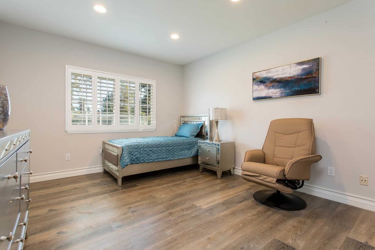 A minimalist bedroom with a single bed, armchair, and modern decor.