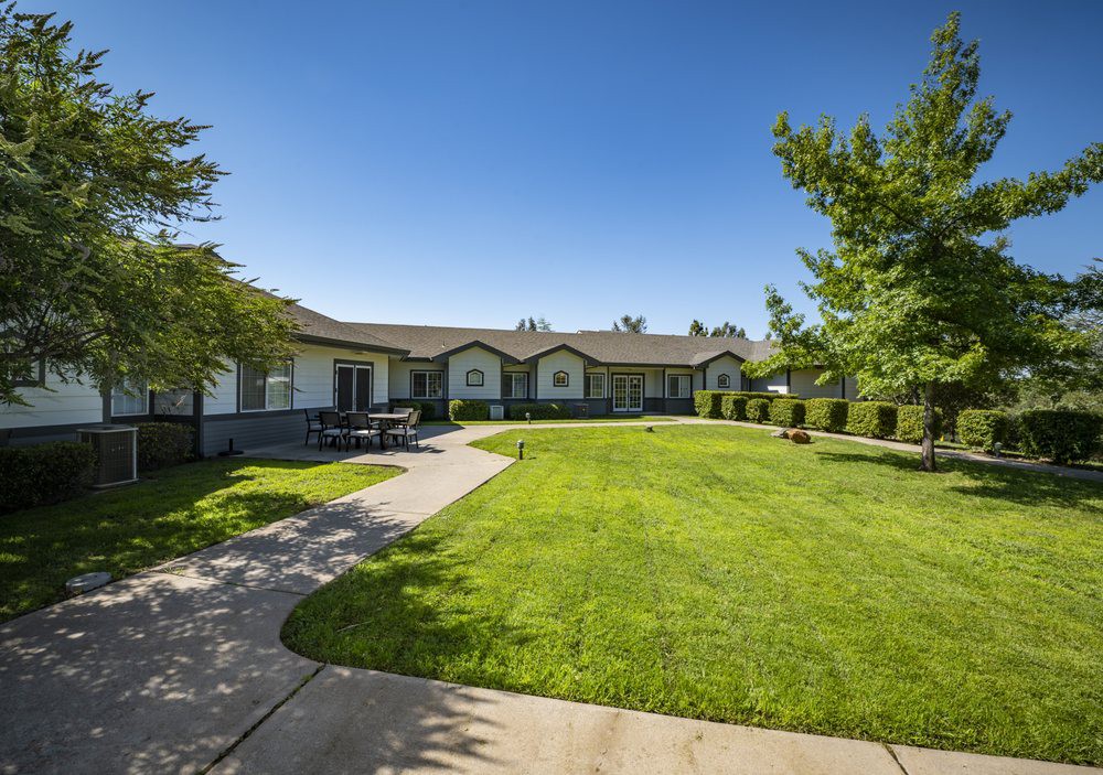 A well-maintained residential building with a lush green lawn and a pathway on a sunny day.
