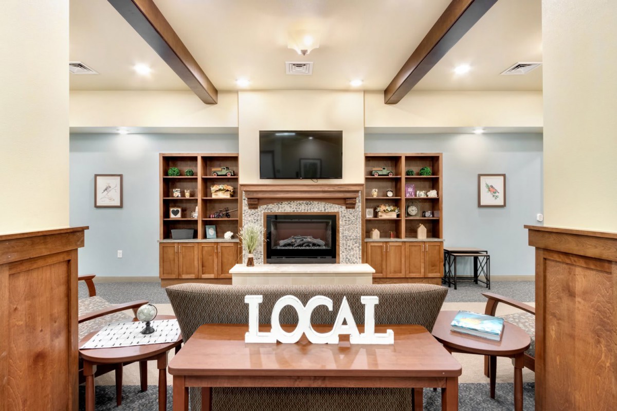 A cozy library interior featuring a fireplace and bookshelves, with 'LOCAL' decor as the focal point.