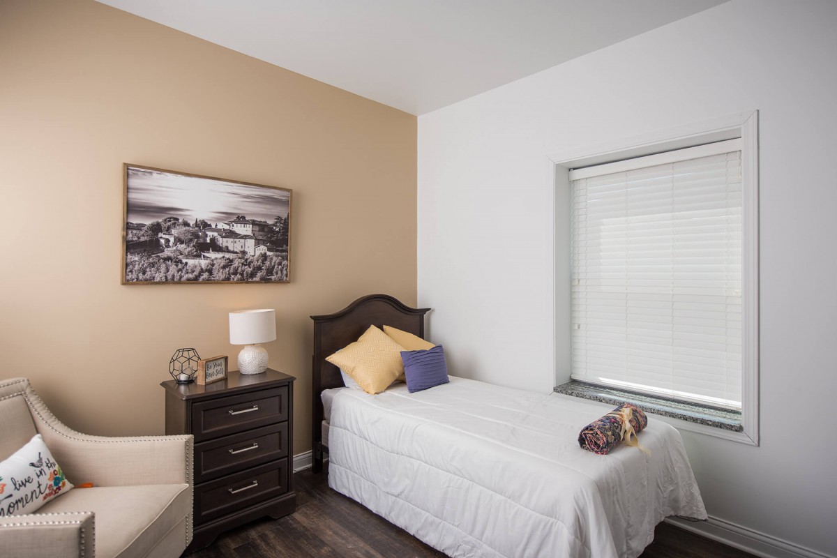 A cozy bedroom with a single bed, nightstand, and window.