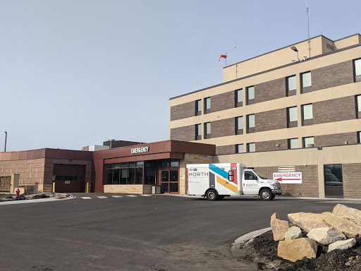 A view of a hospital building with an emergency vehicle parked at the entrance.