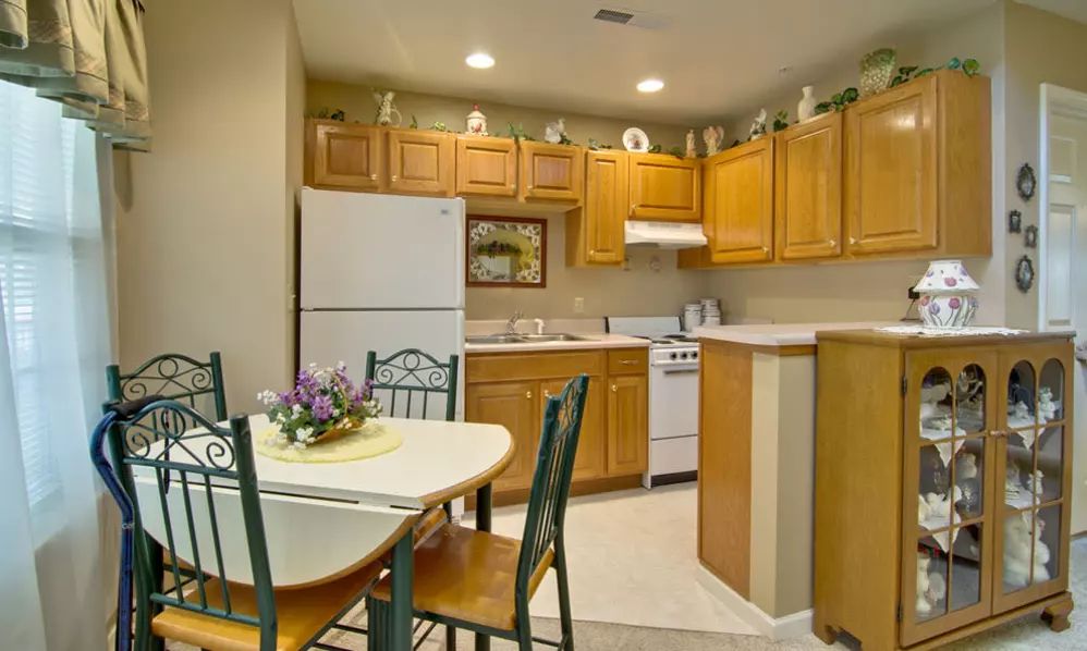 A cozy kitchen with wooden cabinets, a dining table with chairs, and essential appliances.