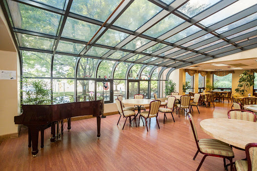 A bright and inviting sunroom dining area featuring elegant furnishings and a grand piano.
