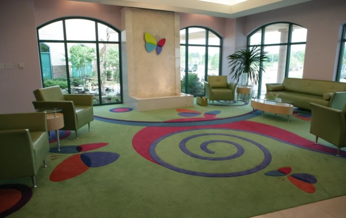 A vibrant waiting area with colorful carpet and ample seating near large windows.