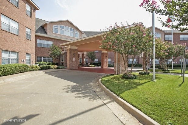 A residential building with a covered entrance and landscaped surroundings.