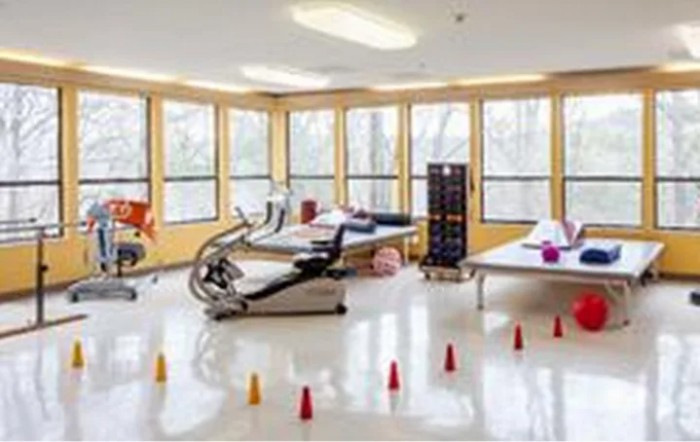 A bright rehabilitation room equipped with various exercise and therapy equipment.