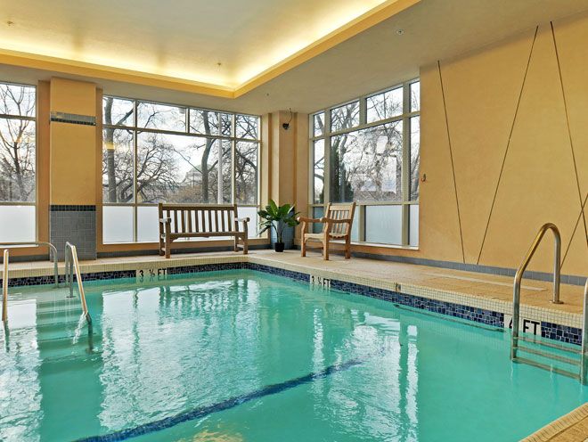 A serene indoor swimming pool area featuring wooden benches and large windows.