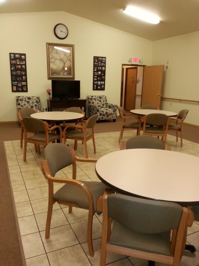 A communal room with tables, chairs, and a television set.