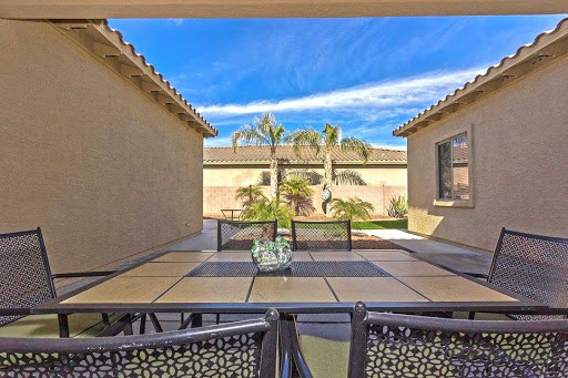 A serene patio view featuring a well-designed outdoor seating area surrounded by palm trees and a clear blue sky.