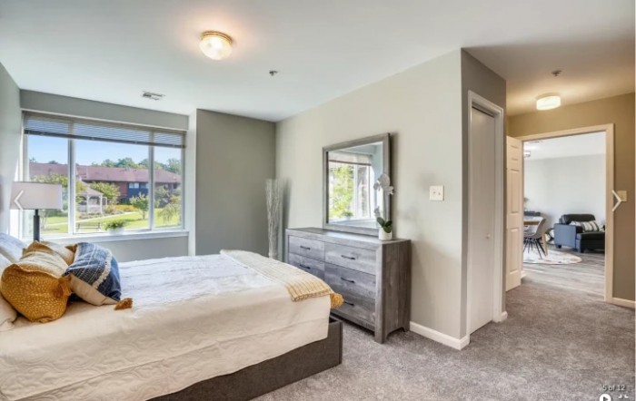 A cozy bedroom with a bed, dresser, and large window.