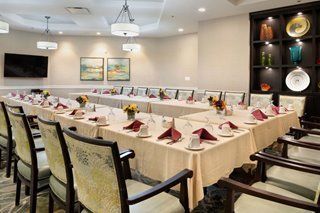 A well-organized conference room with tables arranged for a meeting, featuring elegant table settings and tasteful artwork on the walls.