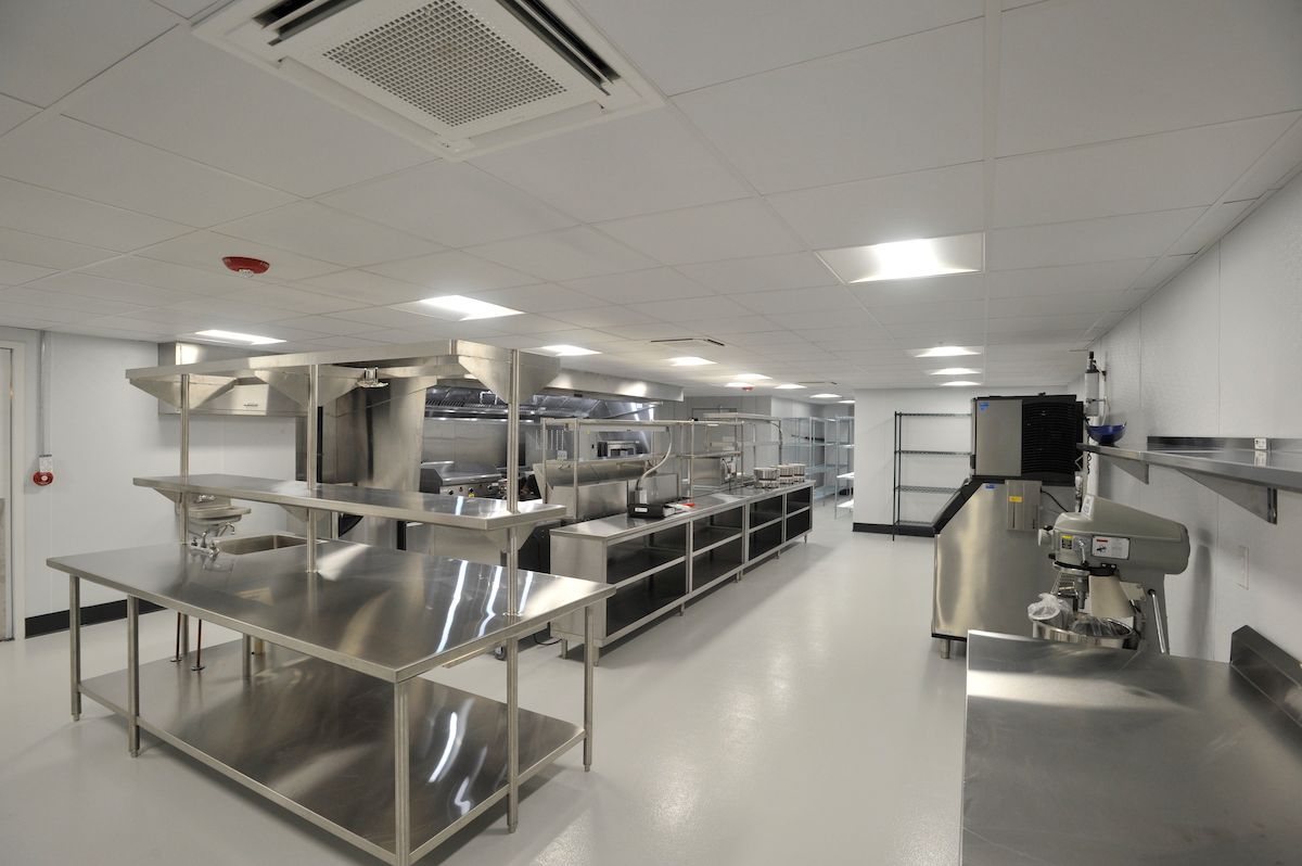 A pristine industrial kitchen with stainless steel equipment and ample workspace.