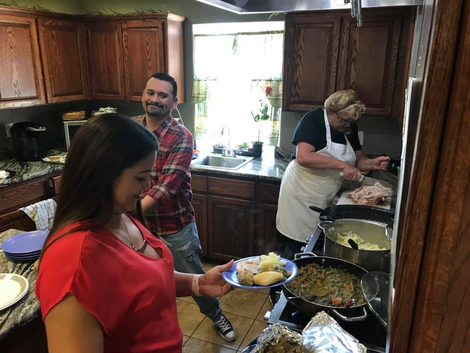 A group of people preparing and serving food in a home kitchen.