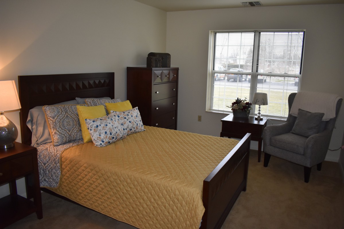 A cozy bedroom interior with a neatly made bed and yellow bedding.