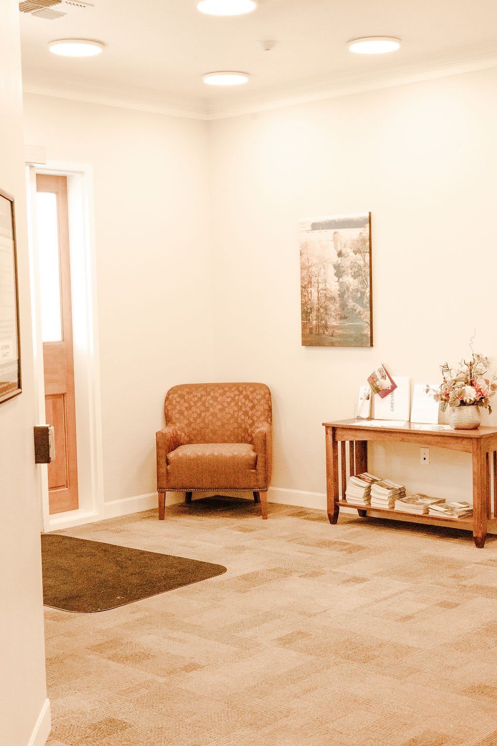 A cozy waiting room with a chair and decorative table.