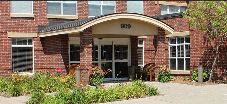 A brick building entrance with decorative landscaping and flowers.