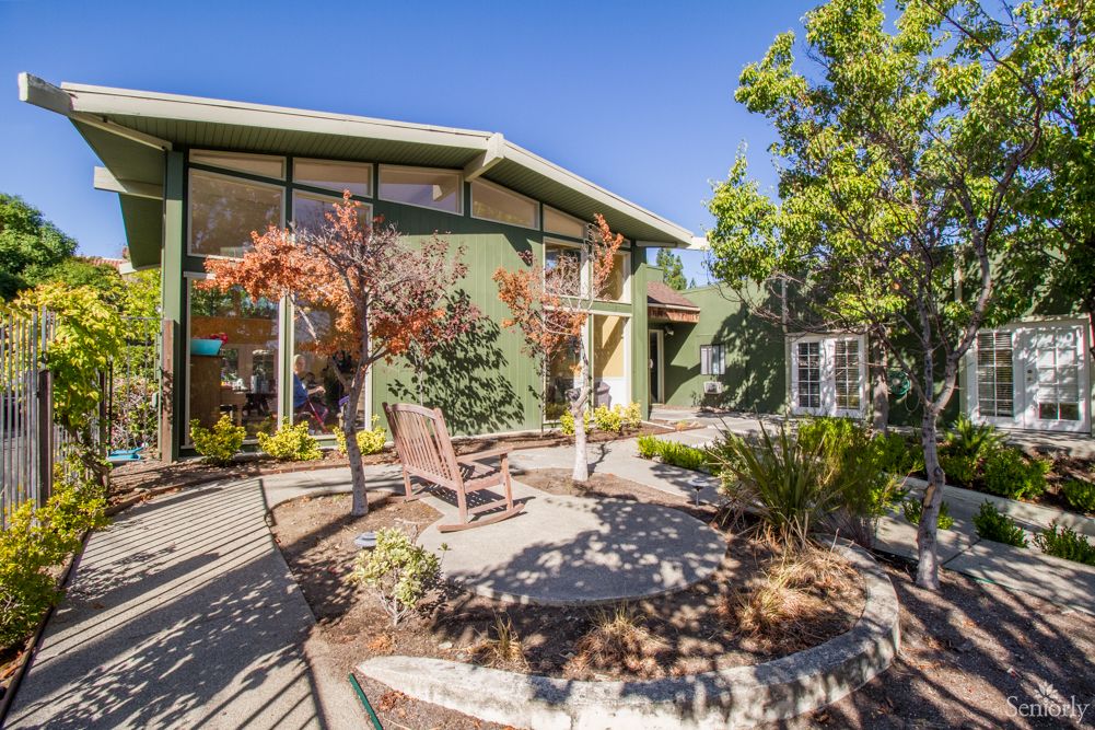 A modern house with a landscaped garden and patio in a sunny setting.