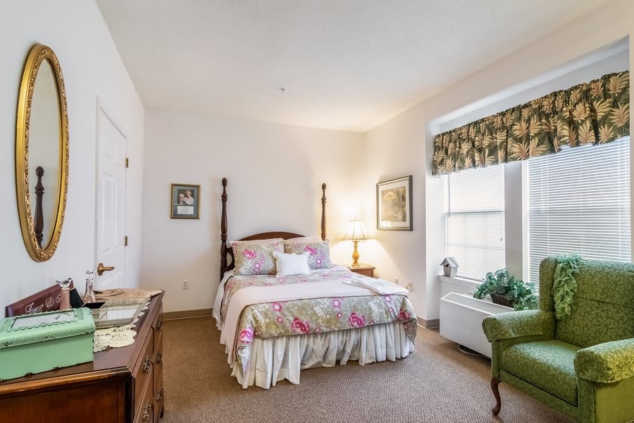 A cozy traditional-style bedroom with a bed, decorative elements, and natural light.