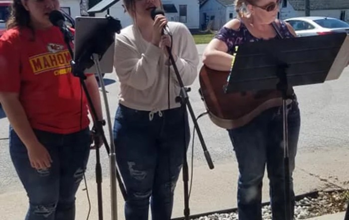 A group of people performing music outdoors with microphones and a guitar.
