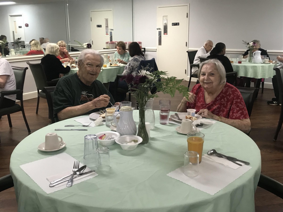 Elderly individuals enjoying a meal together in a communal dining setting.