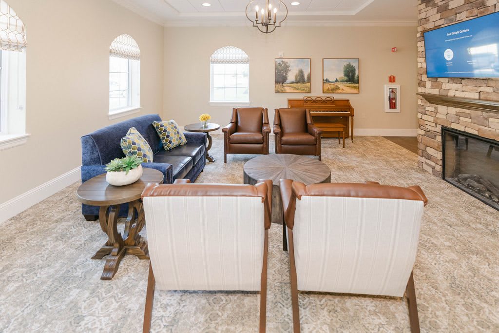 A cozy living room with a sofa, armchairs, and a coffee table, decorated with paintings and plants.