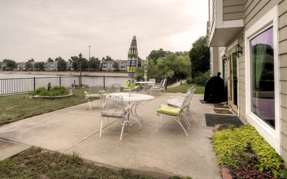 A tranquil patio setting with outdoor furniture overlooking a serene lake.