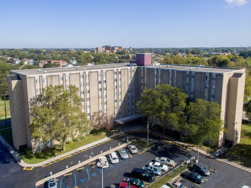 An aerial view of a hotel building surrounded by a parking lot and greenery.