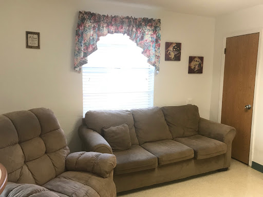 A cozy living room featuring a beige sofa, decorative curtains, and charming wall art.