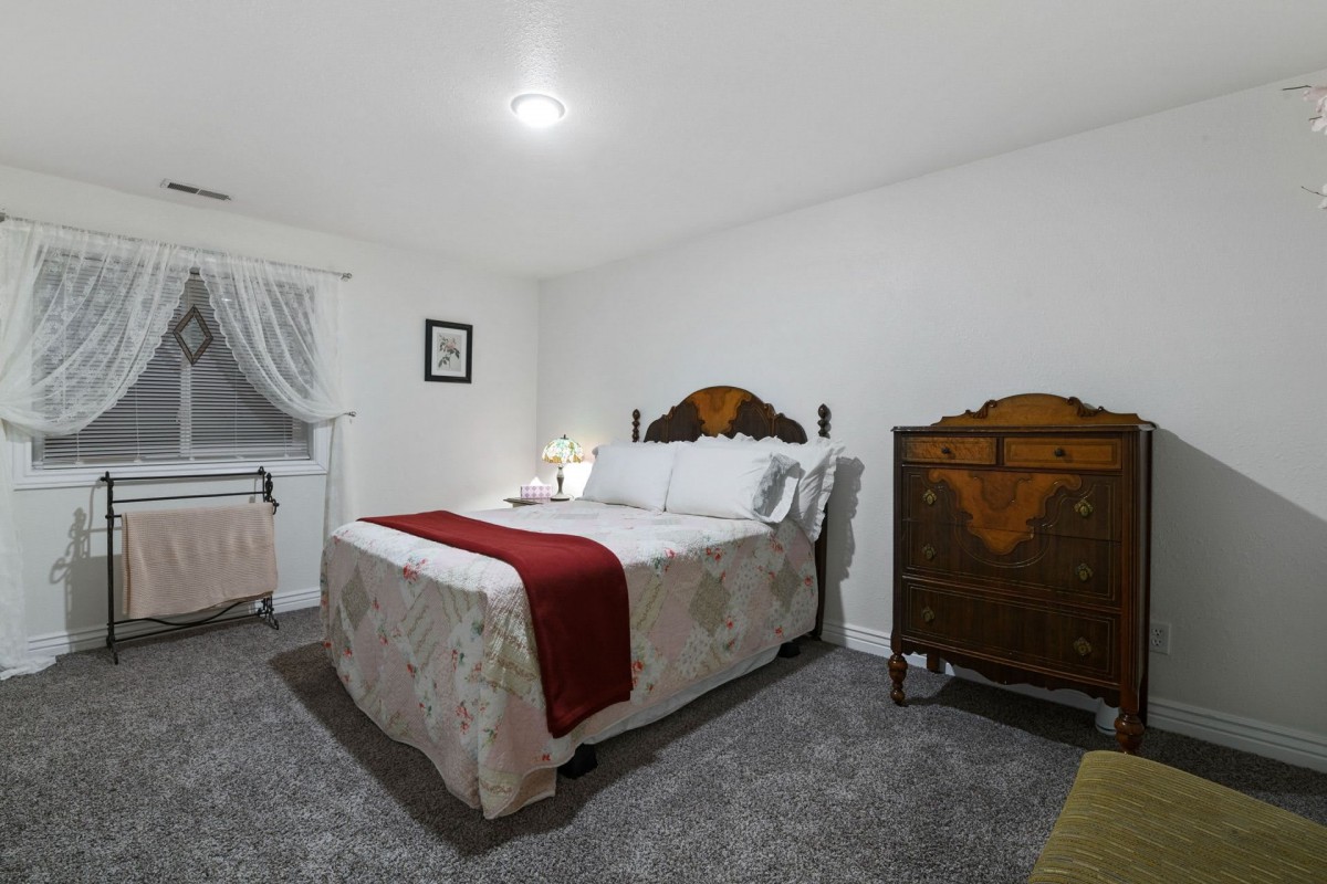 A cozy bedroom featuring a bed with patterned bedding and a wooden dresser.