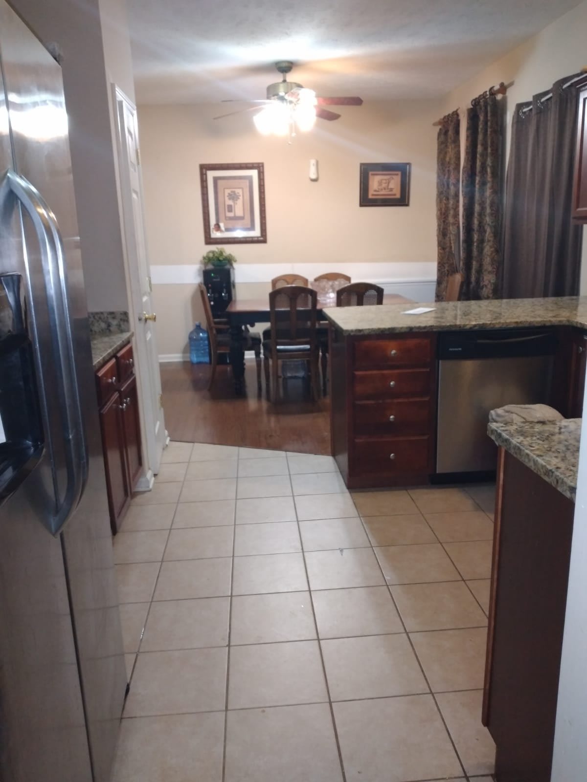 A view of a kitchen leading into a dining area, featuring stainless steel appliances and wooden cabinets.
