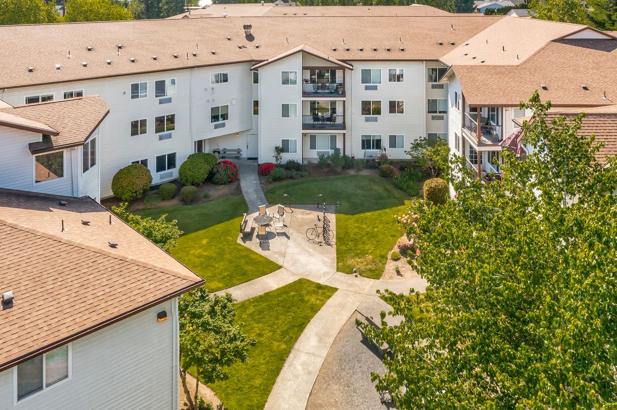A residential apartment complex with a central playground and landscaped pathways.