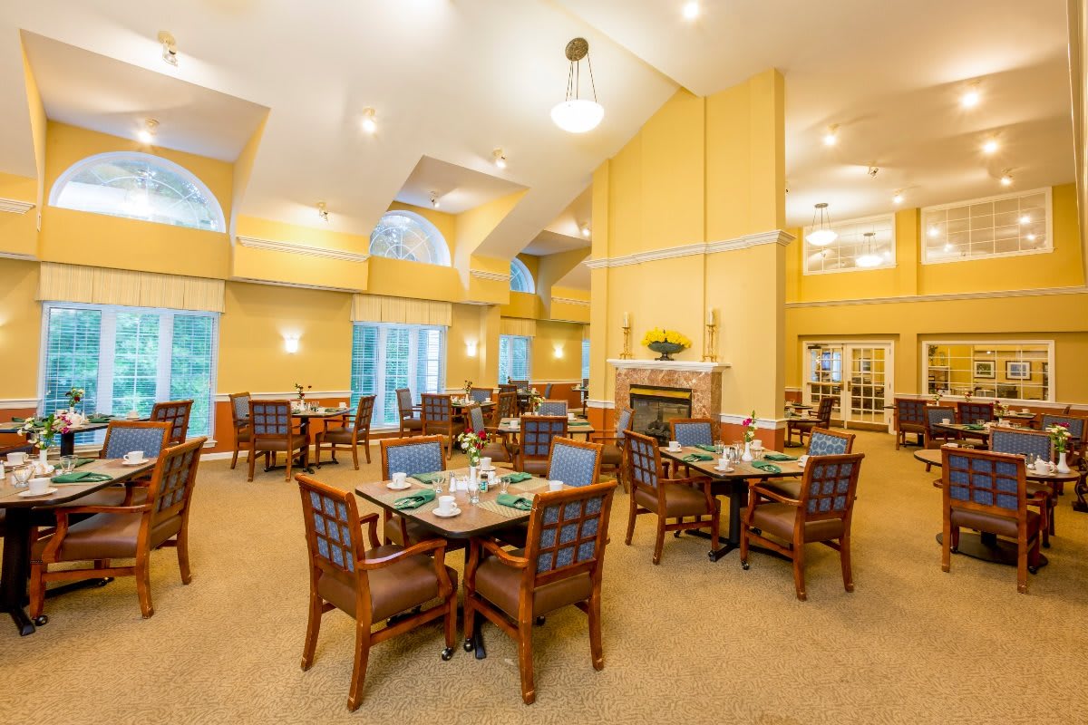 A spacious and well-lit dining room with multiple tables and chairs arranged for guests.
