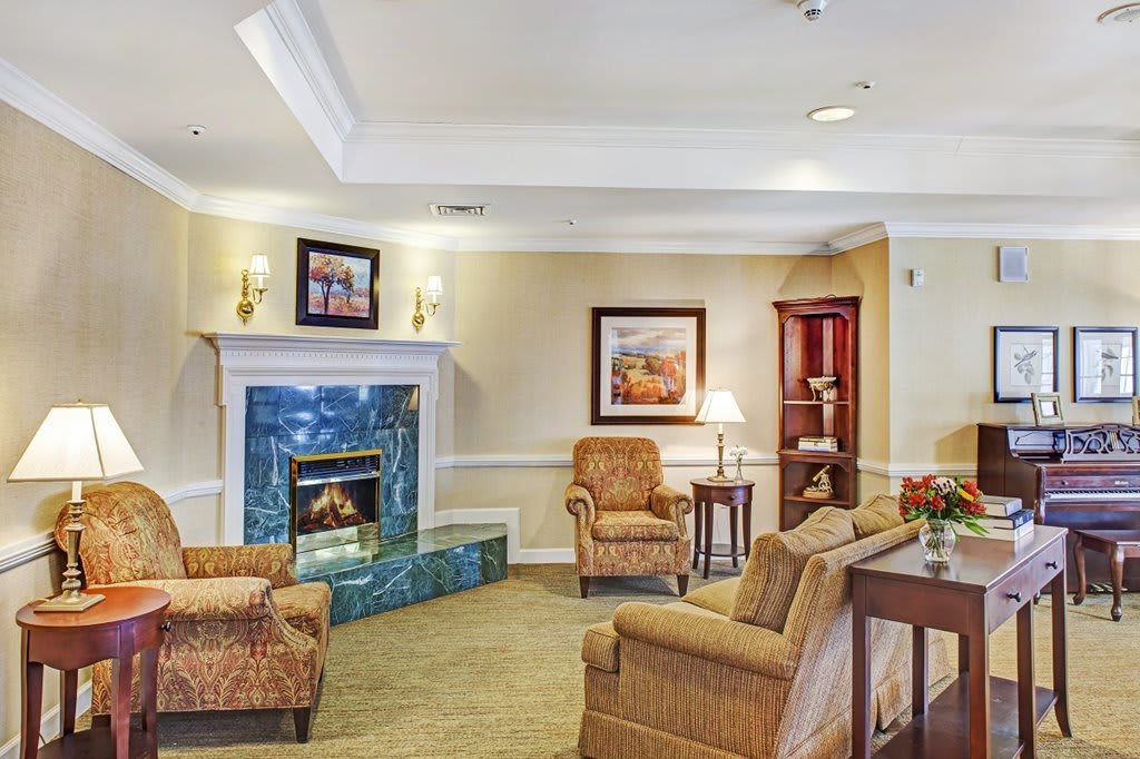 A cozy living room with a fireplace, armchairs, and decorative artwork.